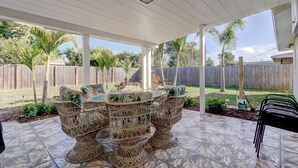 A covered patio with wicker furniture and a stone-tiled floor. -  Few Mins to Madeira Beach, Comfortable, Dog Friendly (Seminole)