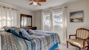 A bedroom with a bed, a chair, a ceiling fan, and a window with curtains. -  Few Mins to Madeira Beach, Comfortable, Dog Friendly (Seminole)