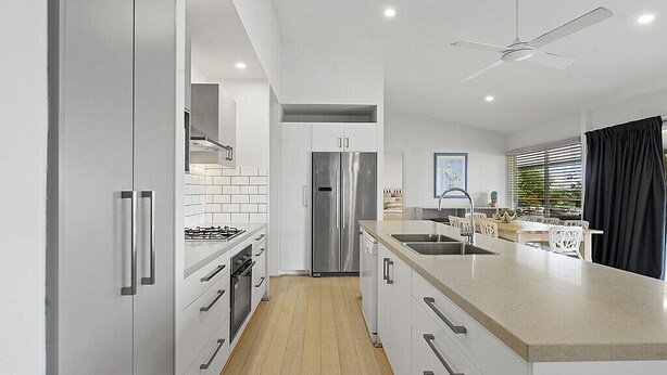 A modern kitchen with white cabinets, stainless steel appliances, and a wooden floor.