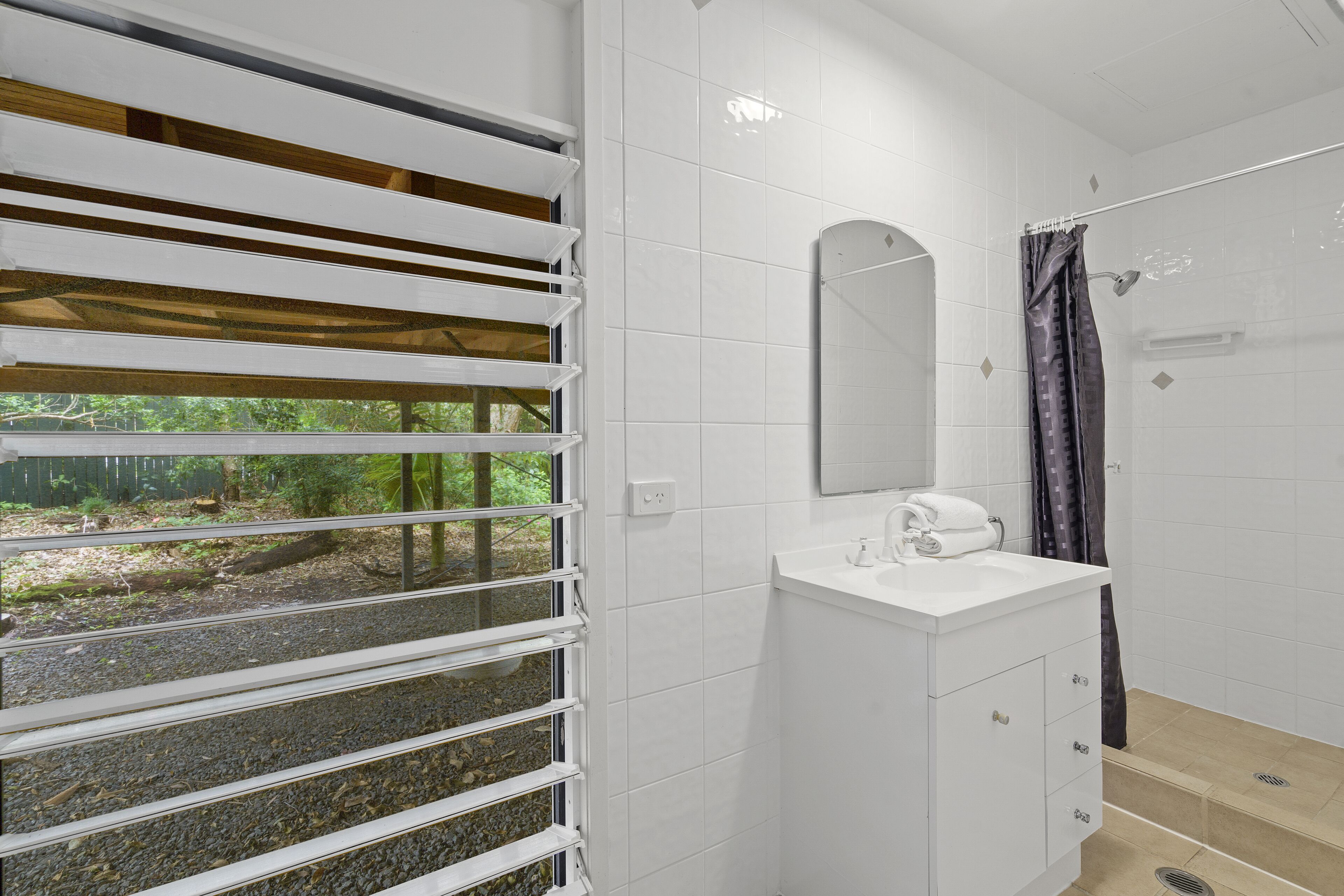 A bathroom with a white sink, mirror, and shower curtain.