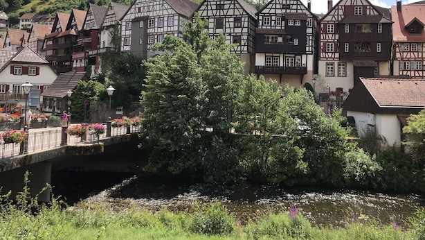 A traditional European town with timber-framed houses, a bridge, and a river.