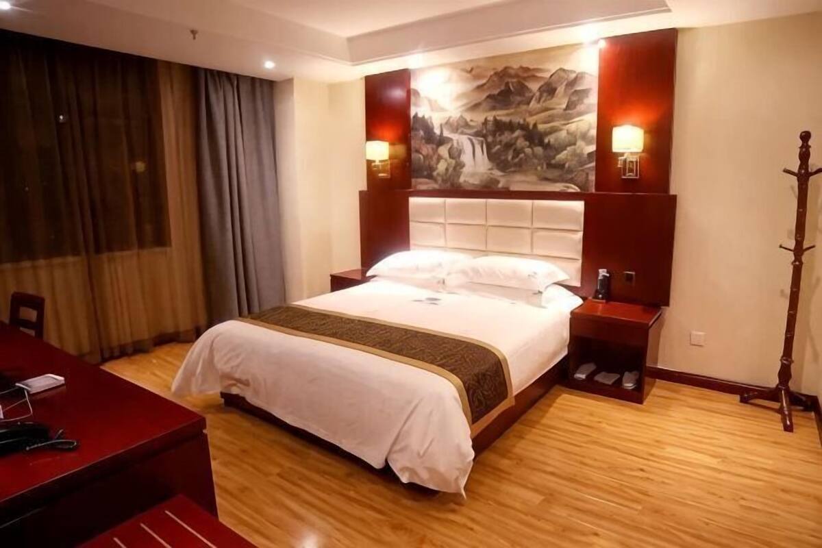 Quarto de hotel com uma cama grande, uma escrivaninha e uma cadeira.
