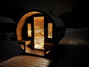 A cozy, circular wooden structure with a warm interior, a bench, and a view of the snowy landscape outside. - Wagner House (Sohland an der Spree)