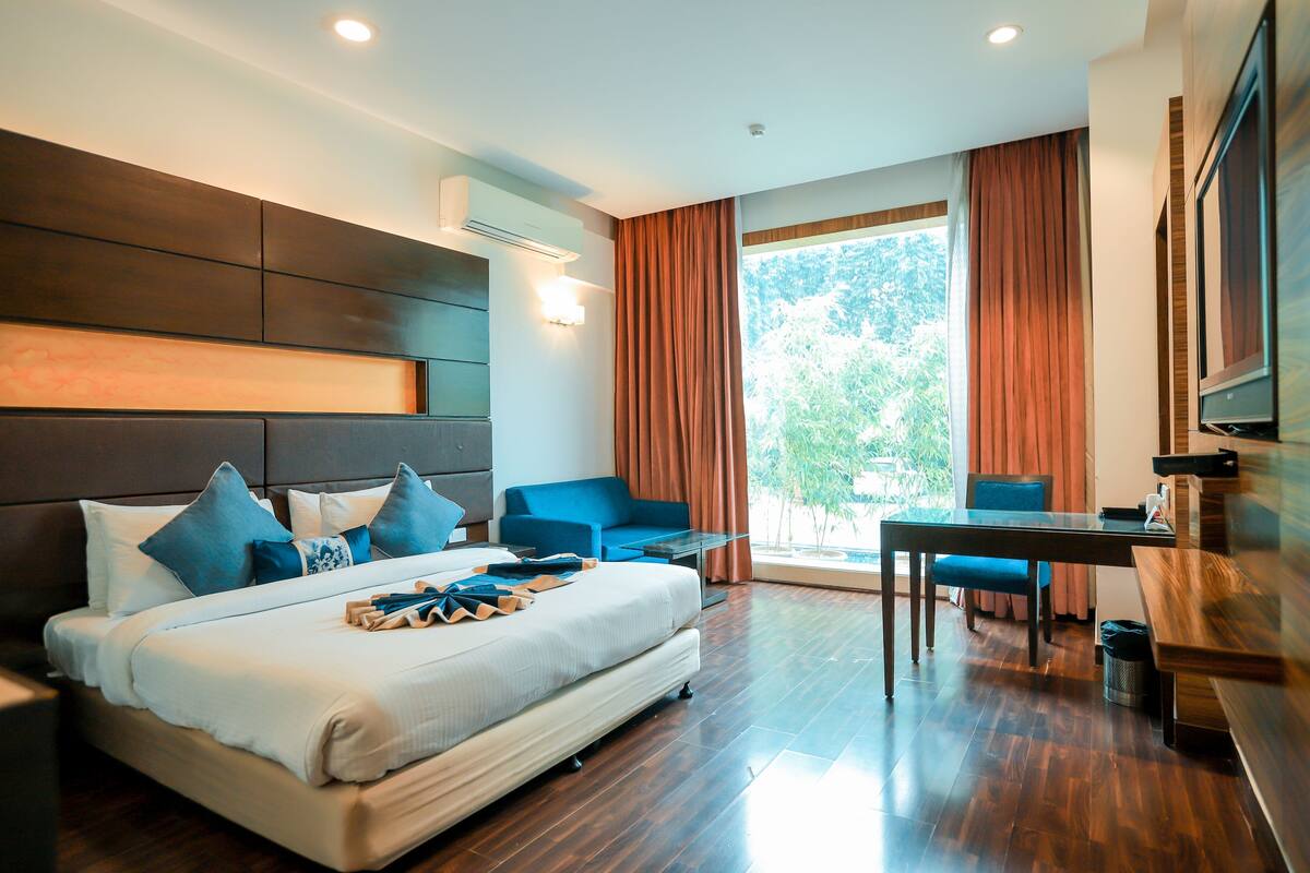 Una habitación de hotel moderna con una cama grande, un escritorio, una silla y un televisor.
