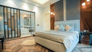 A modern bedroom with a large bed, a walk-in closet, and a bathroom with a glass door. - Bel-La Monde Hotel Chhattarpur South Delhi (New Delhi)