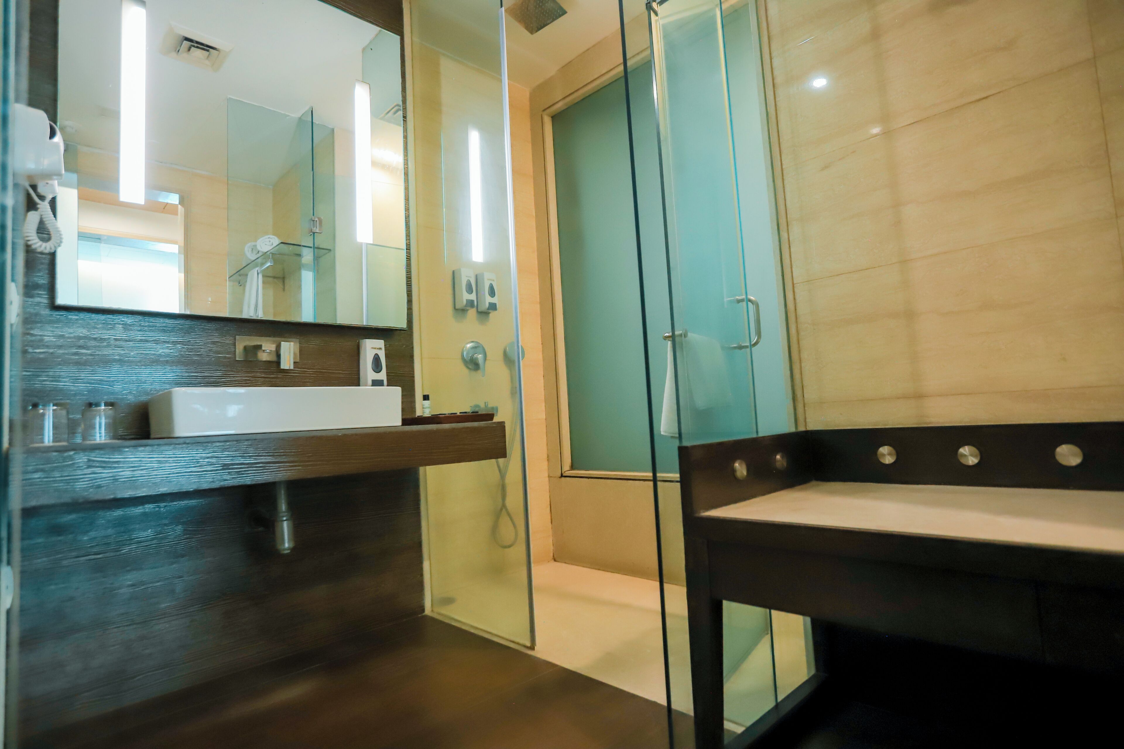 Une salle de bain moderne avec une douche à parois de verre, un meuble-lavabo en bois et un grand miroir.