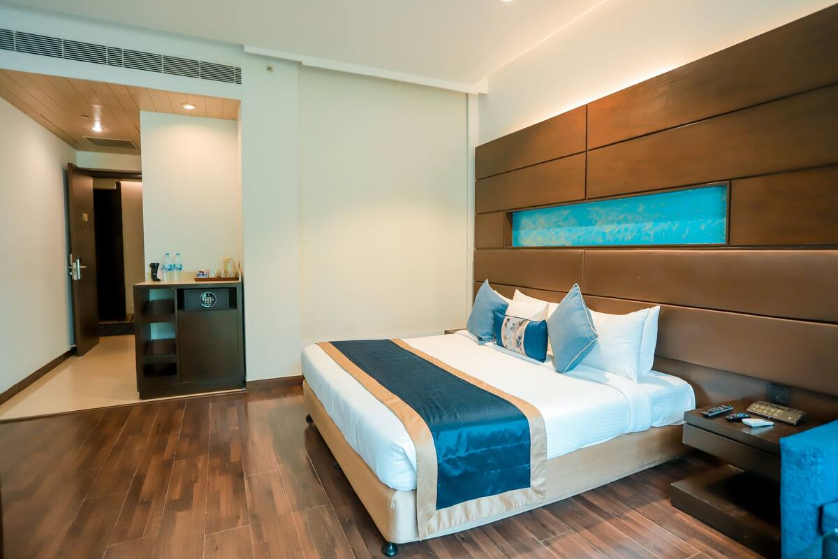 Una habitación de hotel moderna con una cama grande, una mesita de noche y un escritorio integrado con una silla.