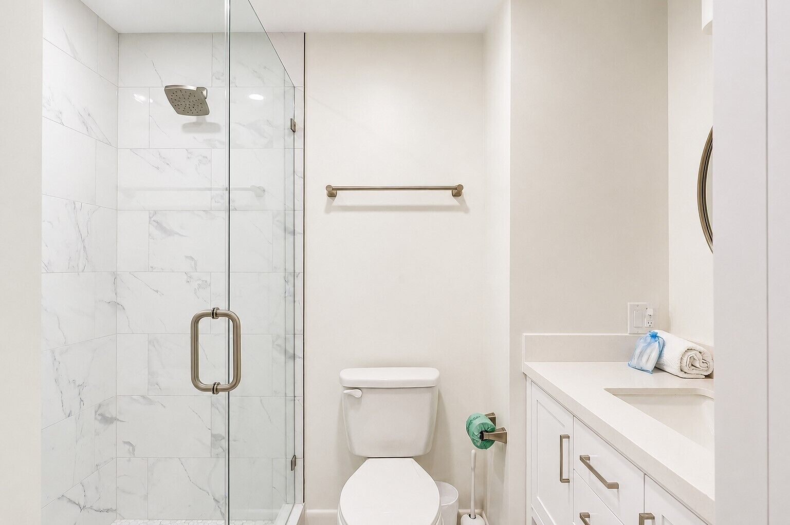 Un baño moderno con ducha de vidrio, inodoro y tocador con dispensador de toallas.
