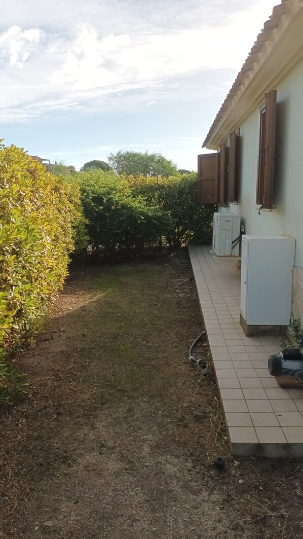 A pathway leading to a building with a tiled exterior and a row of air conditioning units.