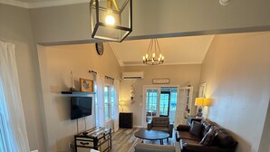 A spacious living area with a dining table, a sofa, and a television. - 3 BR Lakefront house, sandy bottom on Lake Dewey in the Sister Lakes (Dowagiac)