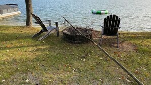 A lakeside setting with a dock, a floating dock chair, a fire pit, and a lounge chair. - 3 BR Lakefront house, sandy bottom on Lake Dewey in the Sister Lakes (Dowagiac)