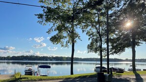 A lakeside parking area with boats and a covered picnic table. - 3 BR Lakefront house, sandy bottom on Lake Dewey in the Sister Lakes (Dowagiac)