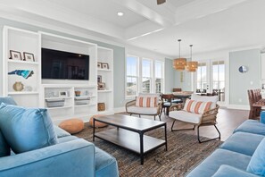 A spacious living room with a large TV, comfortable seating, and a dining area. - Private pool, elevator, stunning views! (Ocean Isle Beach)