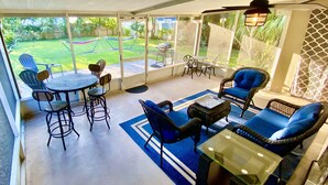 Un patio couvert avec des meubles d’extérieur, un barbecue et une vue sur le jardin.