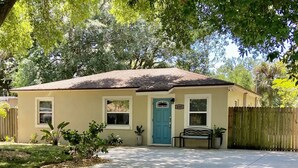 Une maison de plain-pied avec une porte d’entrée bleue, un petit porche doté d’un banc et une clôture en bois.
