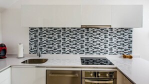 A modern kitchen with white cabinets, a patterned backsplash, a stainless steel sink, and a built-in oven. - Dream 2BR PH! Steps to Beach! Downtown location! (Playa del Carmen)