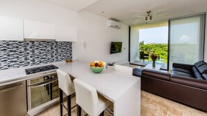 A modern kitchen with a dining area, a large window with a view, and a living area with a sofa. - Dream 2BR PH! Steps to Beach! Downtown location! (Playa del Carmen)