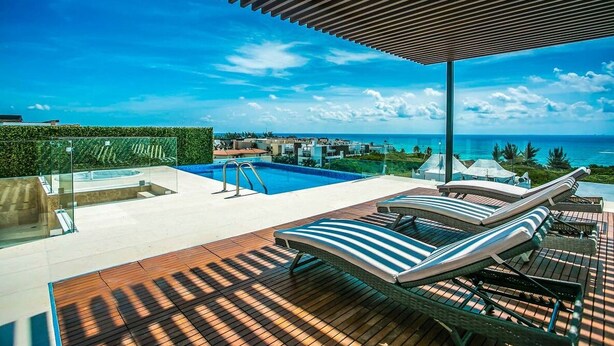 A rooftop pool area with lounge chairs, a hot tub, and a view of the ocean. - Dream 2BR PH! Steps to Beach! Downtown location! (Playa del Carmen)