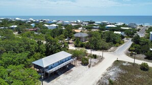 Vue aérienne d’une zone résidentielle côtière, avec des maisons, une plage et une vue dégagée sur l’océan.