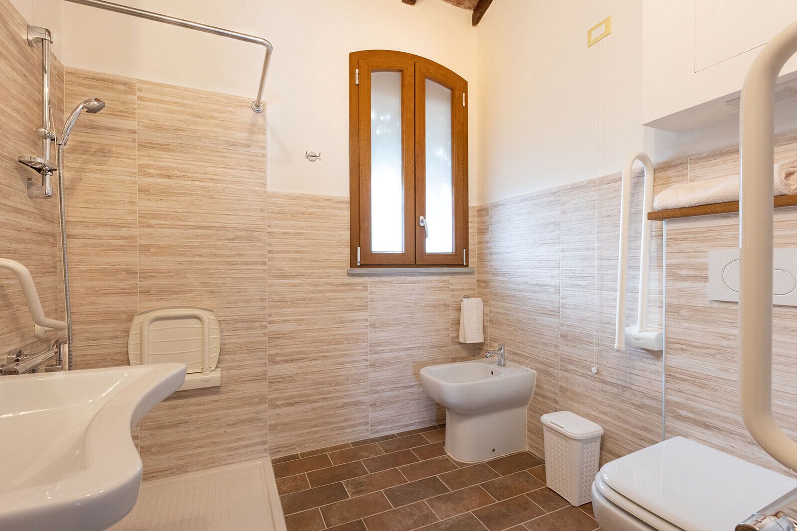 A modern bathroom with a shower, sink, toilet, and bidet.