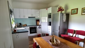 A compact kitchen with white cabinets, a built-in oven, and a refrigerator. - Heritage Timber Cottage - close to shops & amenities (Pemberton)