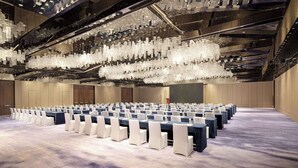 A conference room with rows of tables and chairs, a large chandelier, and a high ceiling with exposed beams. - Wyndham Grand Lishui Downtown (Lishui)