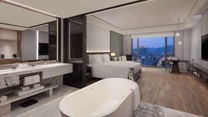 A modern hotel room with a large bed, a bathtub, a vanity with a mirror, and a city view. - Wyndham Grand Lishui Downtown (Lishui)