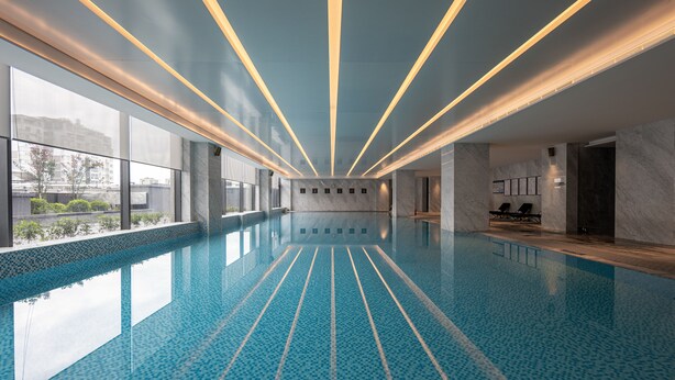A modern indoor swimming pool with a clear view of the cityscape through large windows. - Wyndham Grand Lishui Downtown (Lishui)