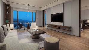 A modern living room with a sofa, coffee table, and TV. There is a city view through large windows. - Wyndham Grand Lishui Downtown (Lishui)