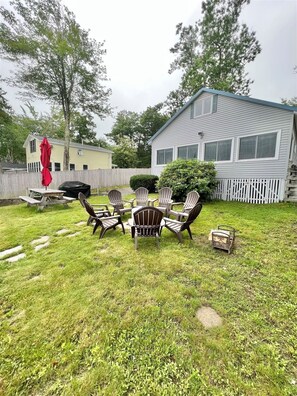 A backyard with a wooden deck, a barbecue grill, and outdoor furniture. - Waterfront on Sebago Lake (Standish)