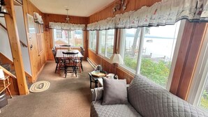 Ein gemütliches Blockhaus-Interieur mit Holzausstattung, einem Essbereich und einem Sofa mit einer gesteppten Dekoration.