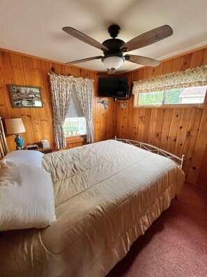 A bedroom with a bed, a ceiling fan, a television, a window with curtains, and a painting on the wall. - Waterfront on Sebago Lake (Standish)