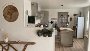 Une cuisine moderne dotée d’un îlot central, d’un coin repas avec une table en bois et d’un îlot de cuisine comprenant un réfrigérateur.