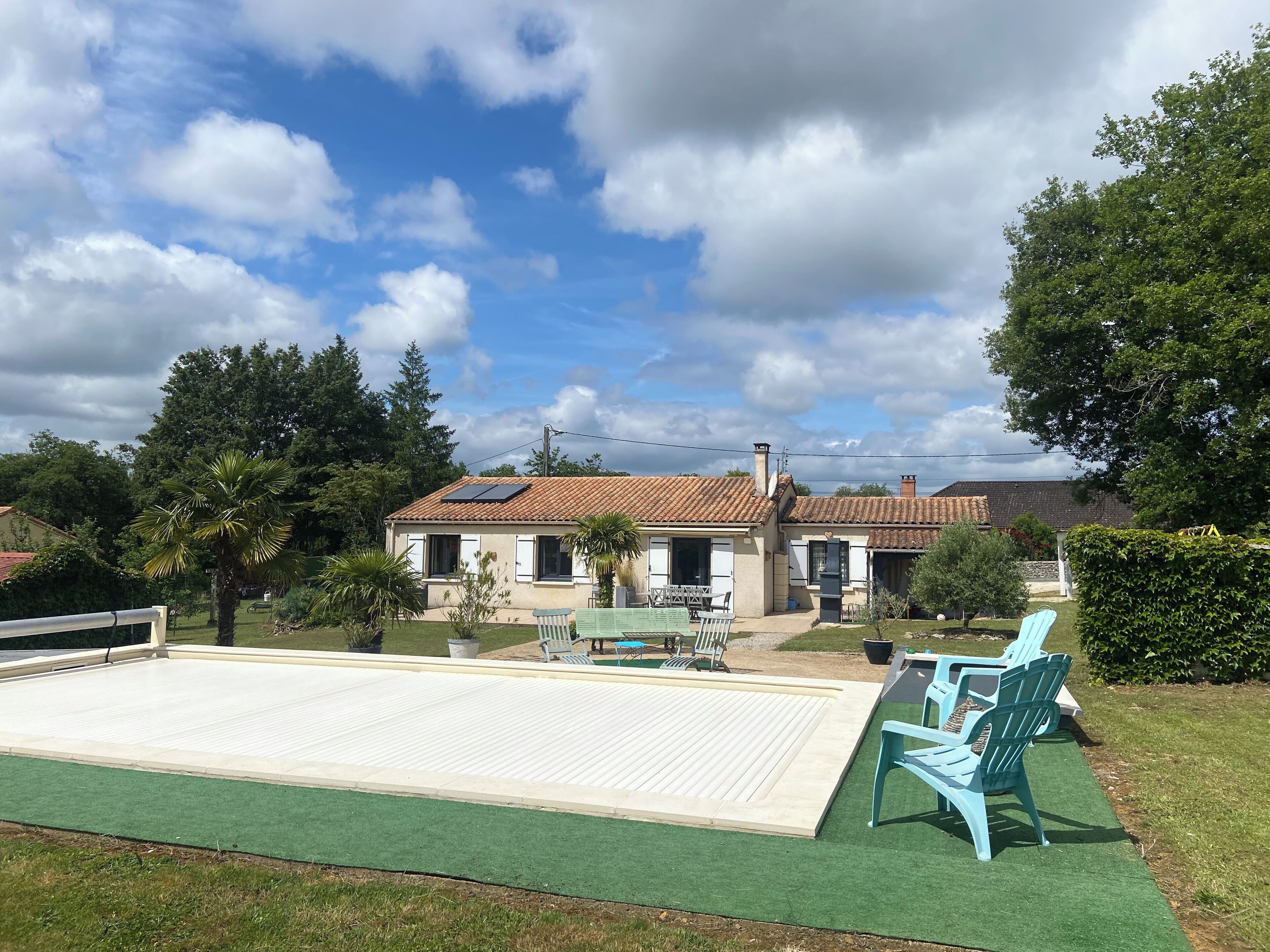 Une maison avec une piscine, du mobilier d’extérieur et un jardin.