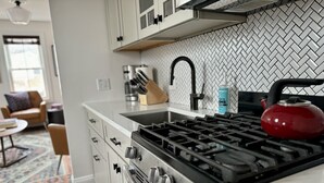 A modern kitchen with a gas stove, stainless steel appliances, and a herringbone-patterned backsplash.