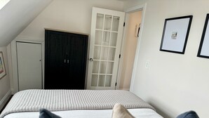 A bedroom with a bed, a wardrobe, a door, and framed pictures on the wall.