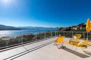A balcony with yellow chairs and a yellow umbrella overlooking a body of water and distant mountains. - Flat by the seaside, large view on the Sagone bay, beach 6 minutes walking (Sagone)
