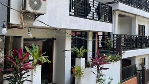 Um edifício com vários andares, varandas, plantas em vasos e um aparelho de ar condicionado.
