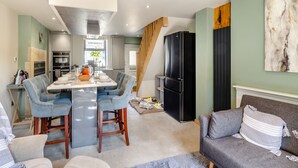 Una cocina moderna con comedor, un refrigerador negro y un sofá gris.