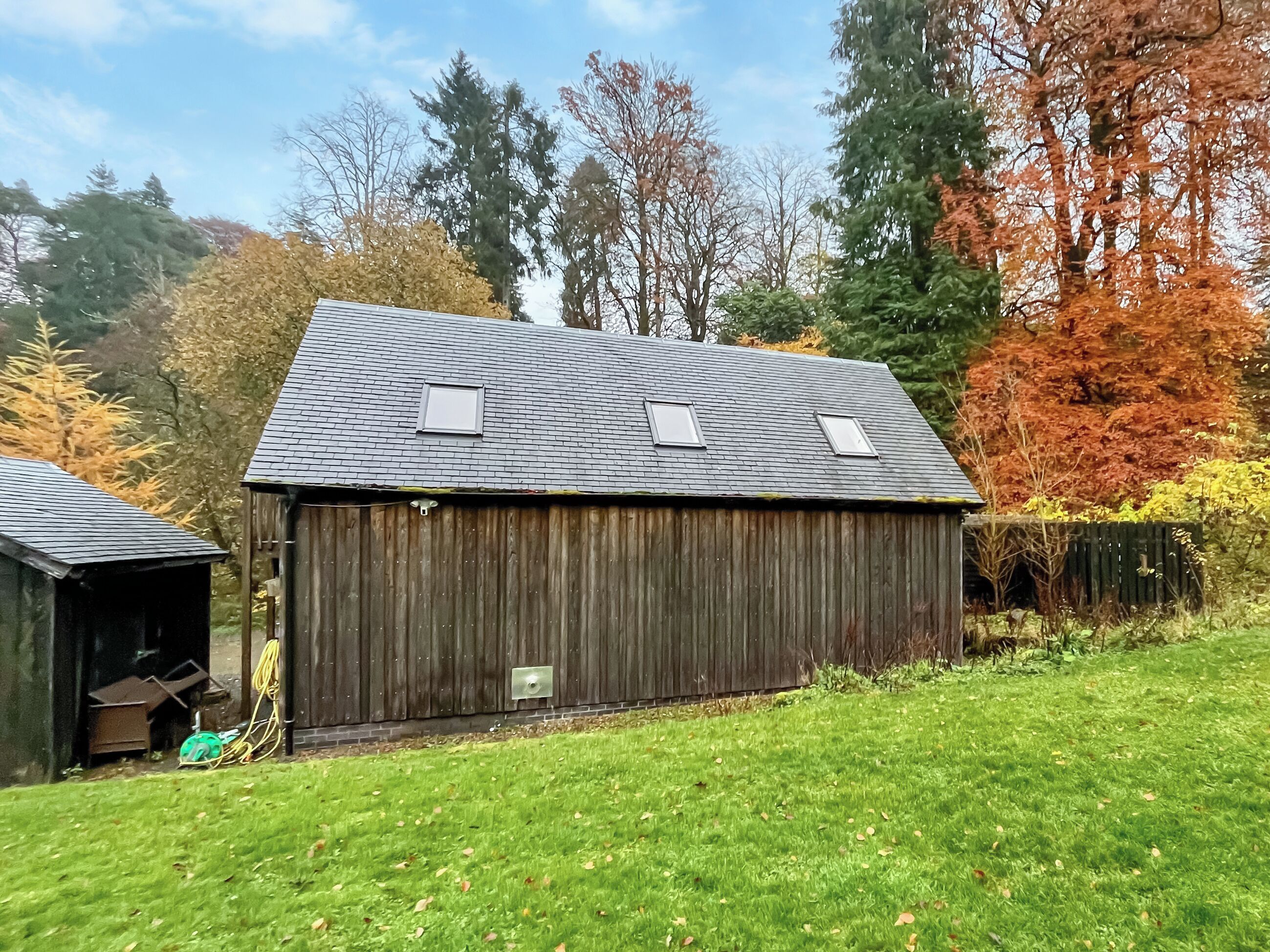 A wooden barn with a sloped roof and two windows.
