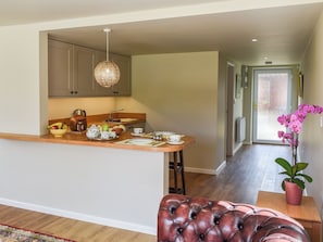 Una cocina moderna con una isla central, un área de comedor con un otoman de cuero y un pasillo que lleva a una puerta.