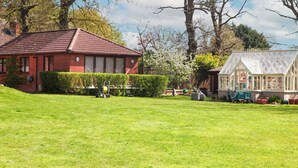 A red brick house with a tiled roof, a green lawn, and a greenhouse. - 1 bedroom accommodation in Strumpshaw, near Norwich (Strumpshaw, near Norwich)