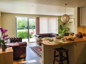 Cocina moderna con comedor, que incluye un sofá de cuero, un taburete de bar y vistas al jardín.