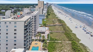 A high-rise hotel with multiple floors, a rooftop pool, and a beach view.