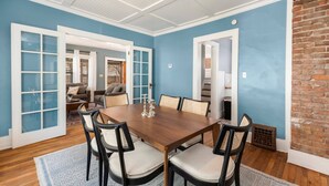 A dining area with a wooden table and chairs, blue walls, and a brick accent wall. - 3 Bed 2 Bath by College Hill w/ Fitness Room (Wichita)