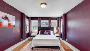 A bedroom with a large bed, purple walls, and a window with curtains. - 3 Bed 2 Bath by College Hill w/ Fitness Room (Wichita)