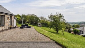 Een stenen huis met een grindpad en een gazon.