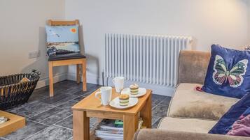 A cozy living room with a wooden table, a cushioned sofa, a chair, and a radiator.