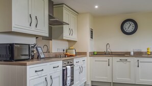 Een moderne keuken met witte kastjes, een magnetron, een fornuis en een spoelbak.