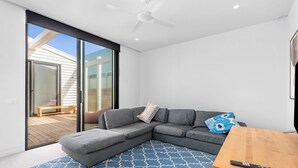 A modern living room with a sectional sofa, a wooden coffee table, and a blue patterned rug. - Gorgeous George Barwon Heads (Barwon Heads)